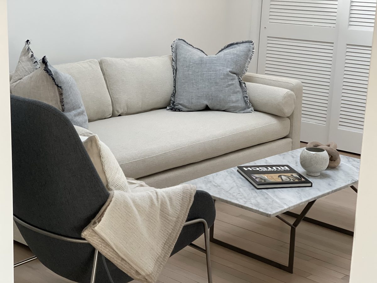 Bright living room with white sofa and plantation shutters by Jameson Anne Interiors